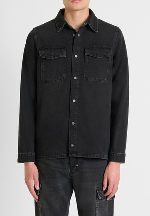 Giacca camicia in denim nero, caratterizzata da un colletto, due tasche frontali con cuciture decorative e bottoni a pressione in metallo.