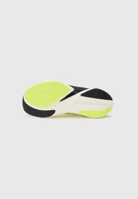 Suela de zapatilla de running negra con acentos en verde brillante y blanco; presenta patrones texturizados y ranuras para tracción.