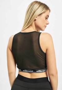 Svart mesh crop topp med en tettsittende design, med en kontrasterende hvit logo-bånd i midjen. Glatt tekstur, uten ermer og kort lengde.