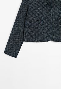 Textured dark blue jacket with a cropped cut, featuring two front pockets and a single button closure, displayed against a white background.
