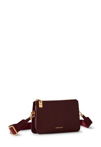 Sac bandoulière en cuir bordeaux avec quincaillerie dorée, fermeture éclair et bandoulière amovible. Présente le logo de la marque à l'avant et une texture lisse.