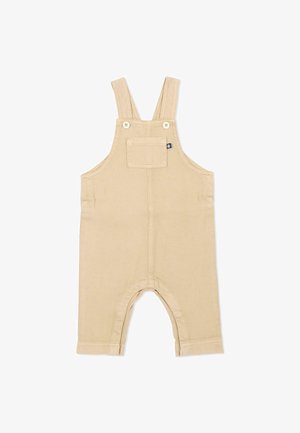 Beige katoenen peuter-overall met voorzak, geknoopte schouderbandjes en korte pijpen boven de enkels.