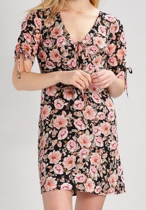 Robe florale avec un fond noir orné de fleurs roses et beige, manches courtes avec nœuds, et décolleté en V. Tissu léger.