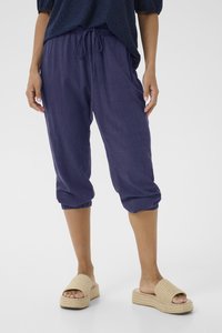 Pantaloni blu navy a culotte con vita regolabile tramite cordoncino e polsini elastici, abbinati a sandali intrecciati beige con suola piatta.