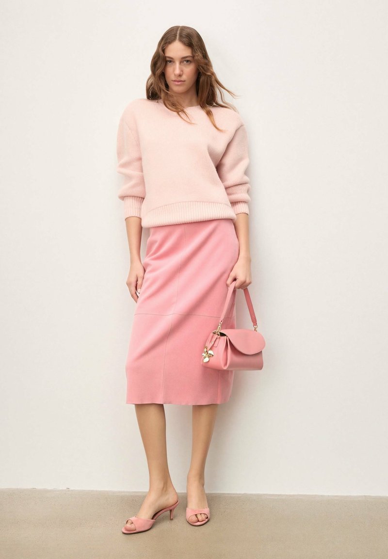 Pull tricoté rose clair, jupe rose ajustée, sac à main assorti et escarpins à bouts ouverts. Textures lisses avec des éléments de design simples.