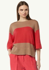 Wełniany top z poziomymi pasami w kolorze czerwonym i beżowym, luźny krój, rękawy o długości trzech czwartych oraz okrągły dekolt.