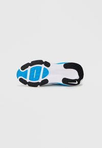 La suola della scarpa presenta un outsole in gomma nera con presa testurizzata, un intersuola bianca e un accento blu. Progettata per offrire trazione e durata.
