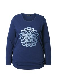 Chemise à manches longues bleue marine en tissu doux, présentant un imprimé mandala circulaire avec des accents argentés et du texte dans une police décorative.