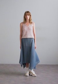 Uten ermer, rosa paljett topp kombinert med et flytende, blått, plisserte skjørt. Modellen har på seg kremfargede joggesko. Enkel, moderne design og lett tekstur.