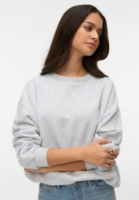 Gaiši pelēks džemperis ar garām, uzrullētām piedurknēm un ribotu apkakli. Uz krūtīm neliels teksts un mīksta auduma tekstūra.