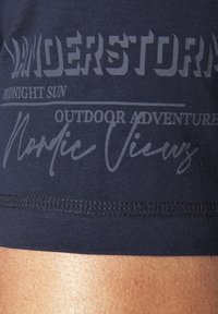 Navy blue fabric with a smooth texture, featuring white graphics that read "WANDERSTORM" and "Midnight Sun" in various fonts.