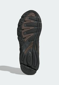 Svart gummisula till sneakers med ett texturerat, vågigt mönster och en brun mellansula för dämpning. Hållbar design för grepp och stabilitet.