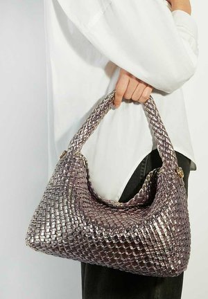 Metallic purple woven handbag with a hobo shape, a textured surface, and a thick shoulder strap, held by a person wearing a white shirt.