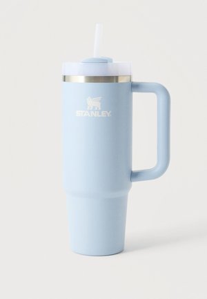 Gobelet de voyage Stanley bleu clair avec poignée, couvercle transparent et paille blanche sur un fond clair uni.