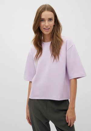 Lichtpaarse T-shirt met korte mouwen in een relaxte pasvorm, gemaakt van textuurstof. Gecombineerd met donkergroene broek. Eenvoudige halslijn en stiksels.