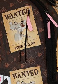 Zaino nero e marrone con finitura strutturata, caratterizzato da manifesti "WANTED" e zip rosa. Illustrazione di un personaggio dei cartoni animati di stile.