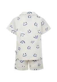 Bomullspajamas-set i en ljus gräddfärg med blåa leende ansiktsmönster, kortärmad skjorta och matchande shorts med upplagda fållar.