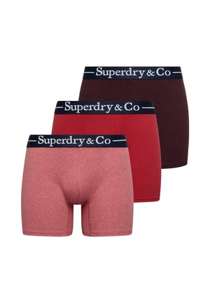Drie paar herenboxershorts in tinten roze, rood en donker bordeaux met zwarte taillebanden gelabeld "Superdry & Co".