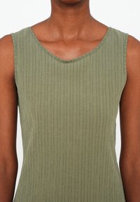 Rochie verde fără mâneci, cu decolteu în V, având o textură ribbed și un material moale, ușor. Design simplu, adaptat pe corp.