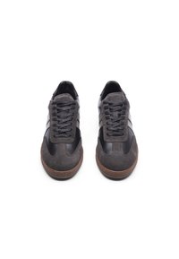 Svart og grå sneakers laget av lær og semsket skinn, rund tå, snøring, og gummisåle med en teksturert brun aksent.