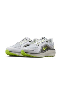 Scarpe sportive in rete bianca con dettagli verdi, texture trapuntata sulla parte superiore, dettagli riflettenti e suola in gomma testurizzata.