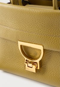 Oliivirohelise tekstuurse viimistlusega nahast käekott, millel on kuldse tooniga metallist kinnitus ja struktureeritud disain.