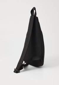 Sort sling taske med et net-tekstureret panel, justerbar rem og robust hardware. Kompakt design, der er velegnet til hverdagsbrug.