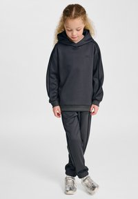 Mörkgrå sweatshirt och matchande byxor i slät tyg. Huva design med ribbad avslutning på ärmar och nederkant, i kombination med silverfärgade sneakers.