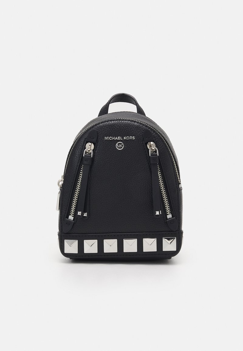 Mini-sac à dos en cuir noir Michael Kors avec deux fermetures éclair verticales à l'avant et des clous carrés argentés le long du bord inférieur.