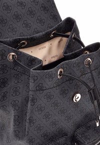 Zwarte stoffen emmer tas met gestructureerd patroon. Voorzien van goudkleurige hardware, trekkoordsluiting en een beige binnenzijde met logo print.