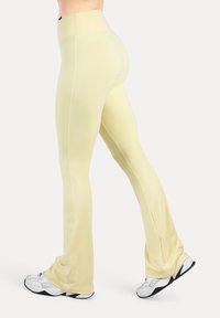 Hoch taillierte, hellgelbe Leggings mit ausgestelltem Design, gefertigt aus dehnbarem Stoff, mit nahtloser Verarbeitung und glatter Textur.