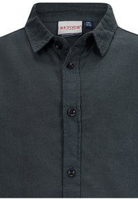 Camicia bottonata verde scuro in tessuto testurizzato, con colletto classico e bottoni neri lungo il davanti. Etichetta del marchio visibile.