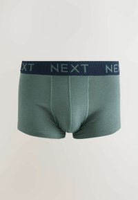 Gröna bomullskalsonger med ett marinblått midjeband där varumärket "NEXT" är tryckt i ljusgrönt. Slät textur och figurnära design.
