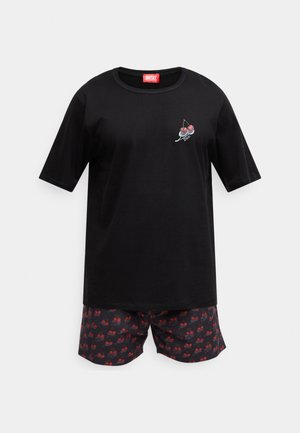 Črna kratka majica s potiskom češenj in rdečo etiketo Diesel. Kombinirana z vzorčastimi kratkimi hlačami, na katerih so rdeče češnje na temnem ozadju.
