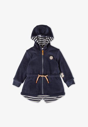 Marineblaues Fleece-Jacket mit Kapuze, gestreifter Innenfutter, orangefarbene Reißverschlussdetails, Kordelzug in der Taille und einem runden Aufnäher mit einem Emblem auf der Brust.