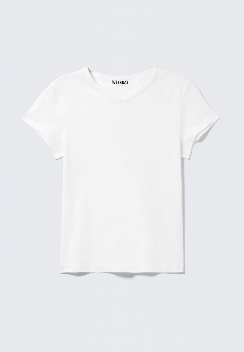 Απλό λευκό κοντομάνικο T-shirt με V-λαιμόκοψη και μικρή ετικέτα "WEEKDAY" στο εσωτερικό του γιακά, εμφανιζόμενο σε ανοιχτό γκρι φόντο.