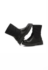 Botas negras de tobillo que presentan una puntera de cuero liso y una parte superior de tela acolchada. Suela de goma gruesa con un agarre texturizado para mayor durabilidad.