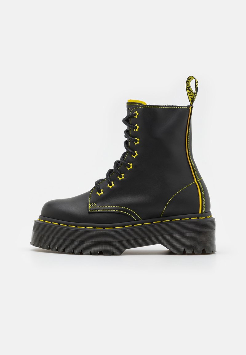 Botte de combat en cuir noir avec semelle épaisse rainurée, coutures jaunes, œillets jaunes pour les lacets et languette jaune à l'arrière.