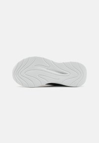Semelle de chaussure de sport blanche avec motif texturé et légère courbure. Présente le logo "SKECHERS" embossé dans la zone du talon.