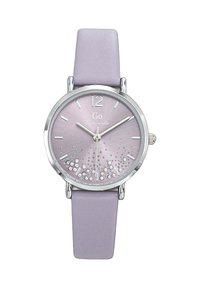 Montre ronde en argent avec un cadran violet clair, des chiffres en argent et des cristaux décoratifs. Bracelet en cuir lavande plat avec une texture lisse.