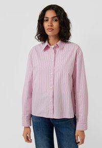 Light pink button-up shirt with vertical white and green stripes, long sleeves, and a collar. Paired with blue denim jeans.