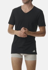 Black cotton V-neck t-shirt with short sleeves, featuring a small white Adidas logo on the lower right. Paired with grey boxer shorts.