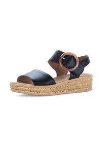 Black leather wedge sandals with a wide open toe, an ankle strap, and a circular brown accent. Textured natural-colored sole.