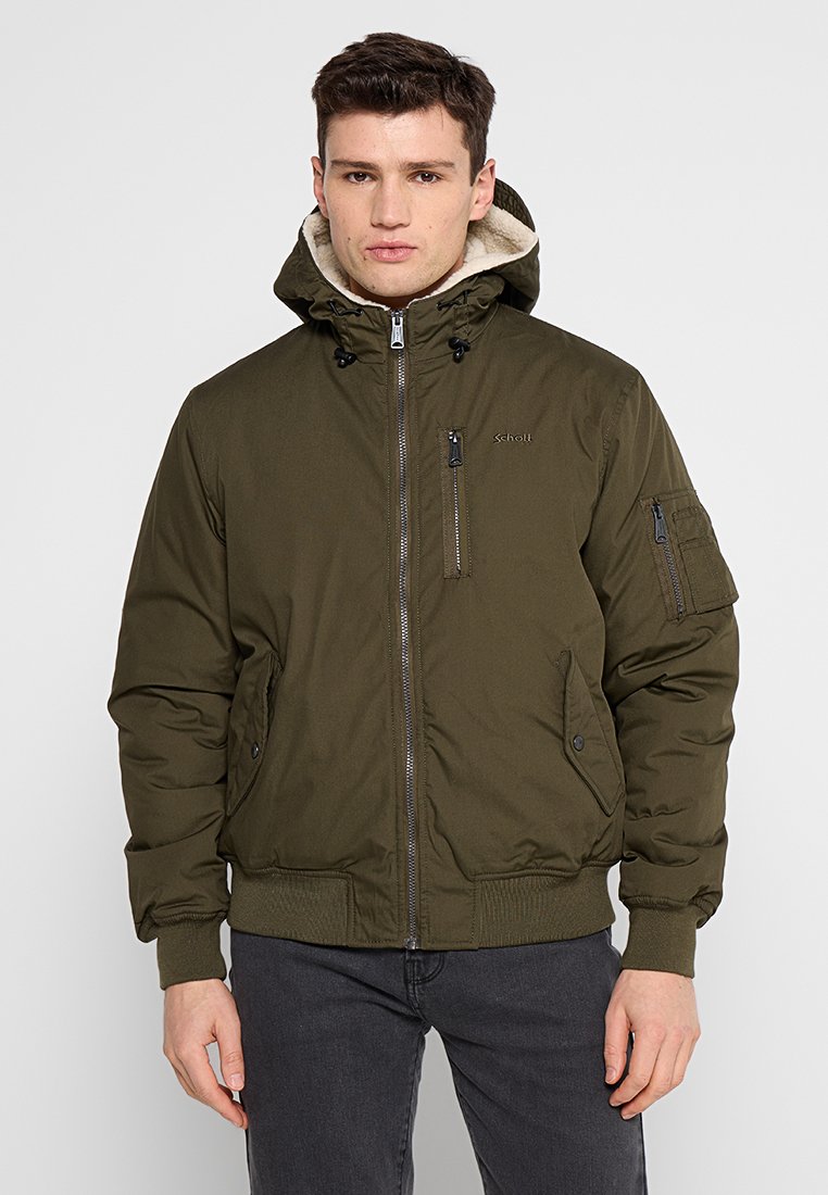 Veste rembourrée verte avec fermeture éclair, capuche ajustable, poches latérales et poignets côtelés. Fabriquée à partir d'un tissu lisse et durable.