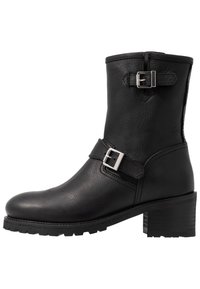 Černá kožená kotníková bota se dvěma stříbrnými sponami, texturovaným povrchem, kulatou špičkou a masivním podpatkem s drážkovou podrážkou.
