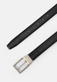 Čierny kožený opasok s krokodíľou vzorkou, vybavený brúsenou kovovou štvorcovou prackou a viacerými otvormi na nastavenie pozdĺž popruhu.