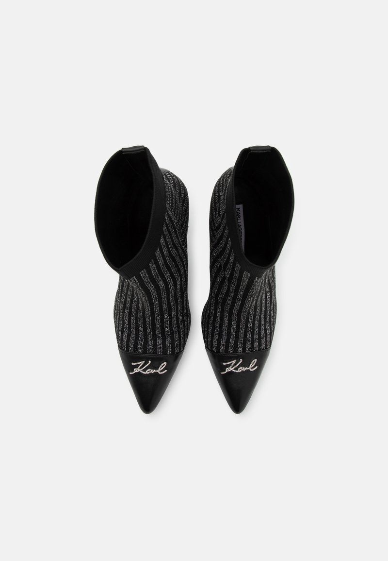 Bottines noires avec un upper en tricot texturé présentant des rayures argentées, un bout pointu et un capuchon en cuir noir avec un détail de logo brodé.