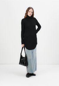 Maglione nero a dolcevita con un motivo a maglia testurizzato, maniche lunghe e orlo curvo, abbinato a una gonna di jeans azzurro chiaro e una borsa nera.