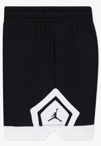 Shorts noirs avec une ceinture élastique, présentant un accent triangulaire blanc à l'ourlet avec un logo Jumpman noir. Tissu texturé.