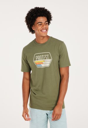 Camiseta de algodón verde, de manga corta, con un gráfico hexagonal que destaca "PROTEST" y rayas de colores. Corte relajado, textura suave.